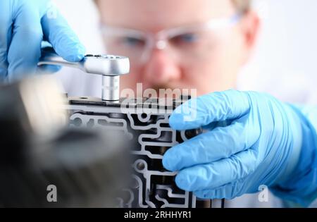 Il centro di assistenza auto riparatore per la riparazione dei cambi automatici tiene la chiave dell'avvisatore acustico manuale esegue il montaggio dello smontaggio. Il dettaglio dell'Hydroblock porta Foto Stock