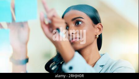 Un'imprenditrice intelligente che pianifica la strategia della sua azienda in ufficio. Giovane donna d'affari sicura di sé e di successo che pensa e. Foto Stock