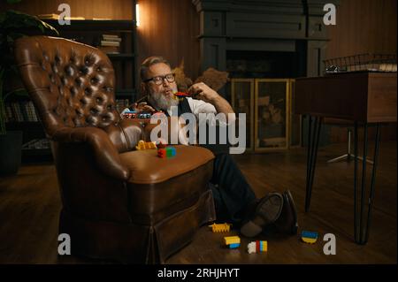 Divertente uomo d'affari anziano che gioca a giocattoli e si diverte dopo una dura giornata di lavoro Foto Stock