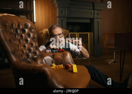 Divertente uomo d'affari anziano che gioca a giocattoli e si diverte dopo una dura giornata di lavoro Foto Stock