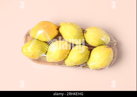 Tavola di legno di pere fresche ricoperta da involucro di plastica su sfondo bianco Foto Stock