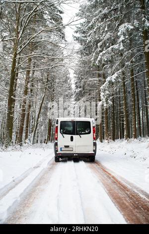 Camper Van guida su una strada attraverso una foresta coperta di neve in inverno, vacanza avventura e stile di vita nei boschi, Germania Foto Stock