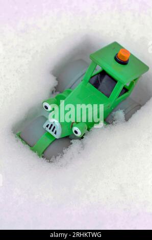 trattore in plastica vintage childs verde sgareggiato nella neve fresca Foto Stock