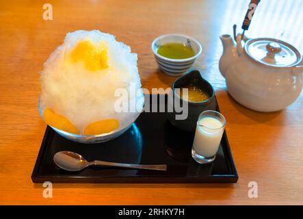 Piatto di un tradizionale dessert giapponese kakig'ri rasato con spicchi di arancia aromatizzata con sciroppo di mandarino pieno di polpa in una marmellata Foto Stock