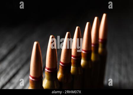 Munizioni, proiettili, munizioni vive per armi da fuoco su sfondo di legno nero, primo piano Foto Stock