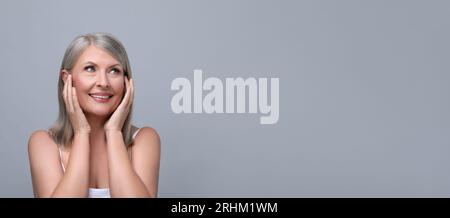 Ritratto di una bella donna matura su sfondo grigio chiaro. Design banner con spazio per il testo Foto Stock