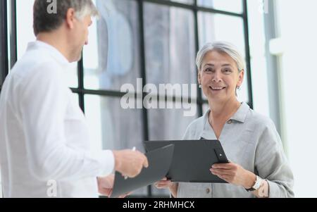 Uomo d'affari e donna d'affari che sorridono guardando il telefono Foto Stock
