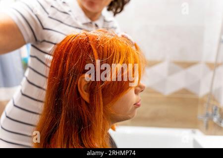 Profilo di una bella ragazza adolescente che si colorava i capelli di rosso. Il processo di tintura dei capelli rossi. Stile e stile moderno Foto Stock