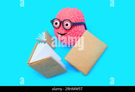 Simpatico personaggio del cervello umano adornato con occhi golosi e occhiali nerd, impegnato nella lettura di un libro. Concetto correlato all'apprendimento e alla curiosità. Foto Stock