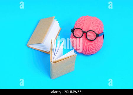 Personaggio del cervello umano adornato con occhiali, impegnato nella lettura di un libro mastro. Concetto di contabilità creativa. Foto Stock