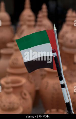 Emirati Arabi Uniti, Abu Dhabi, pentole in terracotta in vendita nel suq iraniano con bandiera nazionale degli Emirati Arabi Uniti. Foto Stock