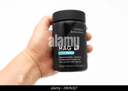 Fuji, Shizuoka, Giappone - 27 maggio 2023: Hand Holding MAG LT Magtein 2000 mg by Sports Research with 90 Vegetarian Capsules. Isolato su sfondo bianco Foto Stock