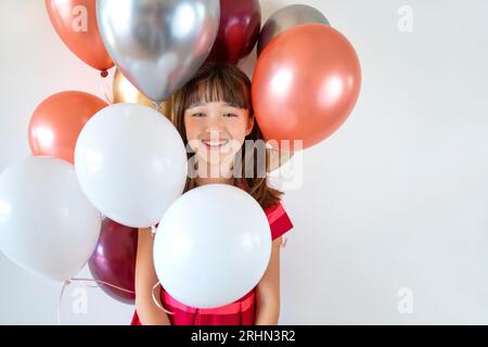 Una bambina di dieci anni circondata da palloncini colorati Foto Stock