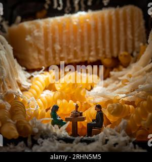 Coppia in miniatura seduto al tavolo della cena circondata da formaggio grattugiato, un'immagine concettuale per la festa ebraica di Shavuot - Pentecoste Foto Stock