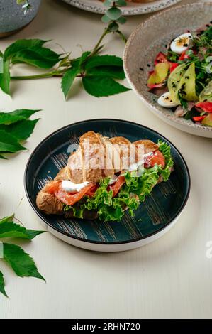 croissant con formaggio spalmabile, salmone, verdure ed erbe. riposati Foto Stock