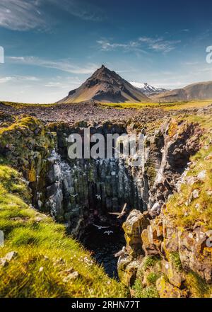 Fantastica vista famosa della montagna vulcanica di Stapafell sopra il buco naturale del nido di gabbiani in estate nella soleggiata giornata della penisola di Snaefellsnes, Islanda Foto Stock