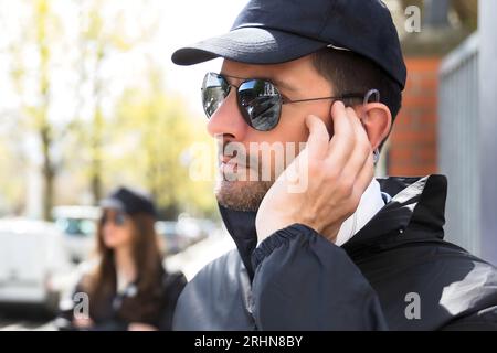 Close-up di un giovane maschio guardia di sicurezza in ascolto con auricolare Foto Stock
