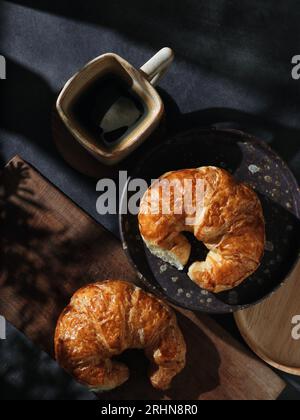 Una tazza di caffè caldo con croissant Foto Stock