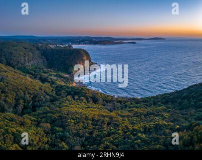 Vista dell'alba sul mare e sulla foresta dal Captain Cook Lookout a Copacabana, sulla costa centrale del New South Wales, Australia. Foto Stock