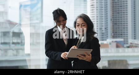 Senior manager della collaborazione per il lavoro di squadra che spiega a un tirocinante per la formazione digitale Foto Stock