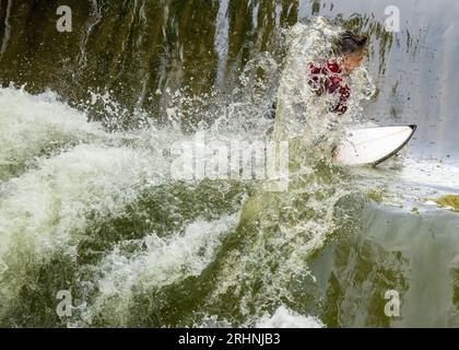 18 agosto 2023, Baviera, Monaco: Un surfista cavalca la sua tavola sull'onda di surf Floßlände vicino al fiume Isar, nel sud della capitale bavarese. Foto: Peter Kneffel/dpa Foto Stock