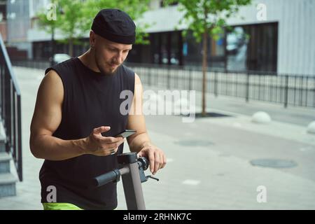 Giovane uomo di città con scooter e telefono su Ability Street Foto Stock