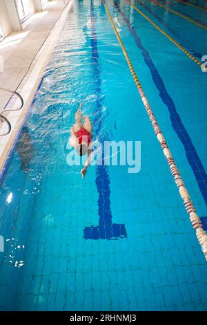 Atleta femminile che fa backstroke nella piscina coperta Foto Stock