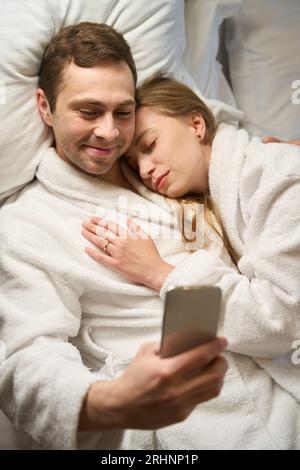 Uomo che ama passatempo serale guardando video divertenti sullo smartphone Foto Stock