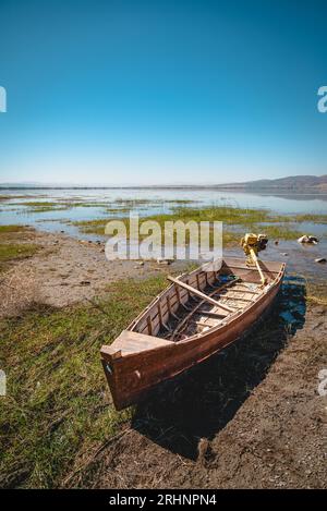 Barca a remi abbandonata su terreno incrinato sul letto del lago seccato a causa del riscaldamento globale e della siccità Foto Stock