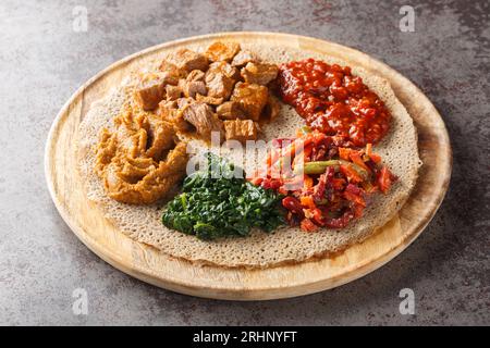 L'Injera è una focaccia a lievito naturale fatta con farina di teff servita con ripieno da vicino sulla tavola di legno sul tavolo. Orizzontale Foto Stock