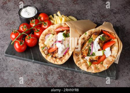 Gyros souvlaki avvolto in una pita pane primo piano sul tabellone sul tavolo. Orizzontale Foto Stock