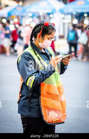 Un cameriere tailandese fa una pausa e controlla il suo telefono su Yaowarat Rd. China Town, Bangkok, Thailandia. Foto Stock