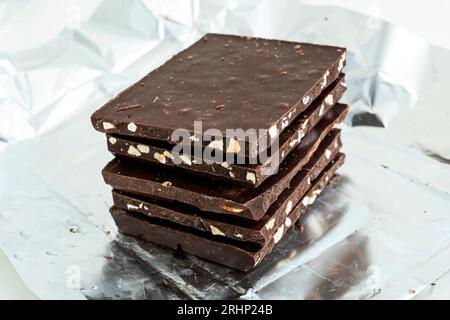 Pila di fette di cioccolato. Torretta di nocciole e latte di mandorle e cioccolato fondente. Concetto fotografico di Sweet food. I pezzi di cioccolato rotto Foto Stock