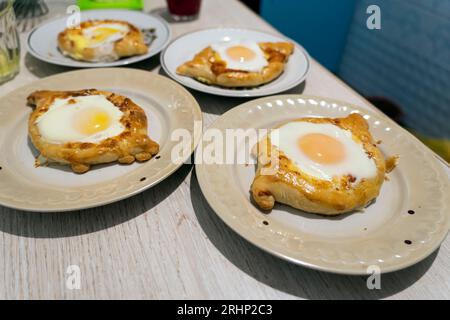 Tradizionale pane georgiano - khachapuri majjarski con fornello hand.fatta in casa cottura. Overhead.Khachapuri con formaggio, georgiano khachapuri megruli con Foto Stock