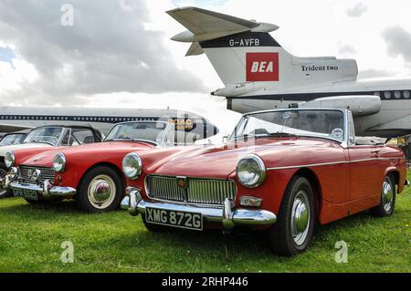 Vintage1969 MG Midget classic car, with Hawker Siddeley Trident 2 airliner jet plane in vintage BEA colours. Nostalgia, old time retro Stock Photo