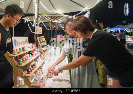 (230818) -- PECHINO, 18 agosto 2023 (Xinhua) -- i clienti acquistano bambole in gesso in un mercato notturno nel distretto di Jiangbei, Chongqing della Cina sud-occidentale, 4 agosto 2023. Chongqing, una città sul fiume Yangtze, è chiamata "stufa" dai cinesi a causa della sua alta temperatura estiva; il Cairo, situato sulle rive del Nilo, è stato a lungo un luogo caldo ai margini del deserto. Entrambe le città hanno promosso vigorosamente l'economia notturna. Hongyadong a Chongqing è un'antica porta della città che è stata trasformata in un gigantesco edificio sospeso con ristoranti e altri luoghi di intrattenimento. Foto Stock