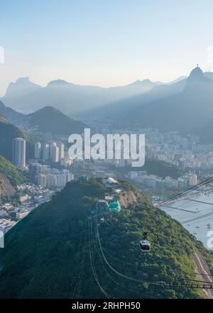 Rio de Janeiro, Brasile: La funivia del Pan di zucchero e la splendida vista panoramica dello skyline della città con montagne, spiagge e quartieri Foto Stock