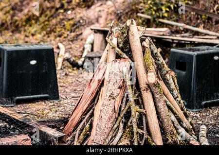 Un falò in un campeggio di una località turistica. Sedie di plastica vuote disposte in un cerchio intorno alla fossa del fuoco. Foto Stock