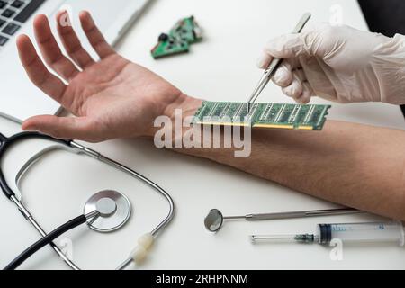 Angolo elevato del medico anonimo nei guanti utilizzando uno strumento moderno per impiantare il microchip RFID blu nella mano del paziente sopra il tavolo con Foto Stock