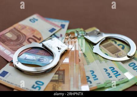 Criminalità e denaro. Le manette sono sul dollaro, euro e rublo Foto Stock