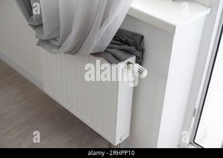 Sotto il davanzale su una parete bianca è presente un radiatore riscaldante con pannello in acciaio. Foto Stock