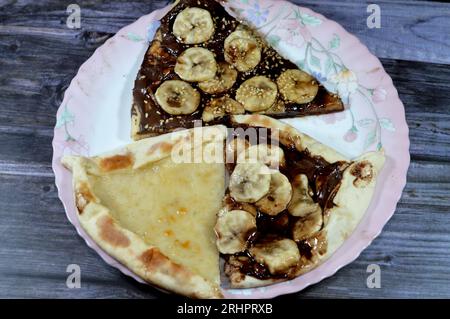 Un piatto di dessert con Una dolce pasticceria di pizza al cioccolato, Chakhtoura, dolce pasticceria al forno, ricoperta di cioccolato, fette di banana, l Foto Stock