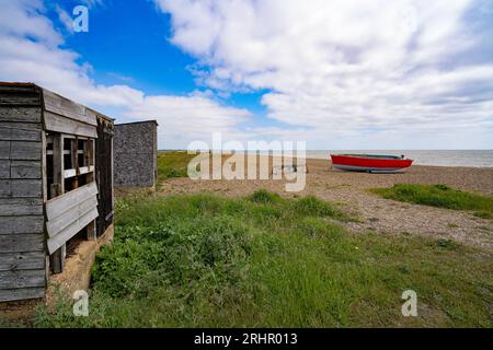 Capanne dei pescatori e barche sulla spiaggia di Dunwich, Suffolk, Inghilterra, Regno Unito Foto Stock