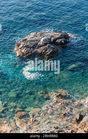 Onde sulla spiaggia rocciosa, riva del mare con onde che si infrangono sulle grandi rocce Foto Stock