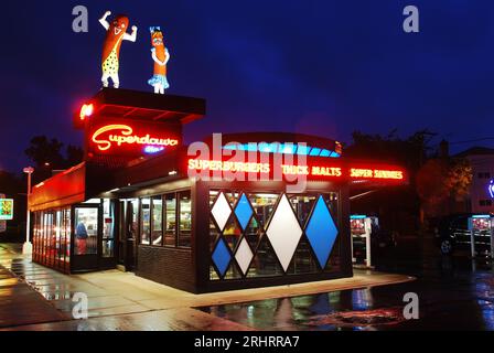 Due grandi hot dog umani si trovano in cima a Superdawg Drive in, Chicago, Illinois, e sono illuminati di notte Foto Stock