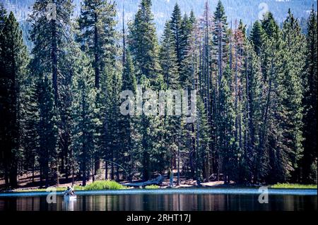 Canoa con gli occupanti a pesca con la mosca sul lago Manzanita nel parco nazionale vulcanico di Lassen. Foto Stock