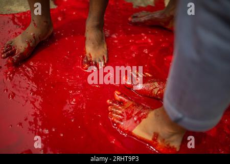 I musulmani immergono i piedi nel sangue dopo aver massacrato un animale per strada a Dacca per il più grande festival musulmano Eid-ul-Azha noto anche come Eid Foto Stock