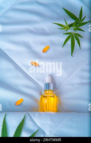 Bottiglia di olio di cannabis, CBD, e una foglia di marijuana, dormendo sotto le coperte. Concetto creativo di prodotti cannabidioli per un sonno migliore e contro l'ingresso Foto Stock