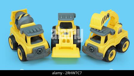 giocattolo di plastica giallo di betoniera e camion di ecavator isolato su sfondo blu. veicolo per costruzioni pesanti. Foto Stock