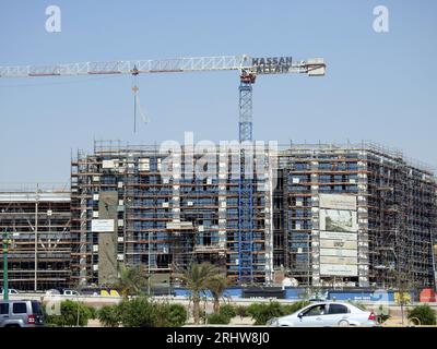 Cairo, Egitto, 21 luglio 2023: Un cantiere di un nuovo edificio industriale con ponteggi e gru di Hassan Allam Construction with the Waving Foto Stock